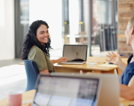 Woman sitting at desk with laptop smiling